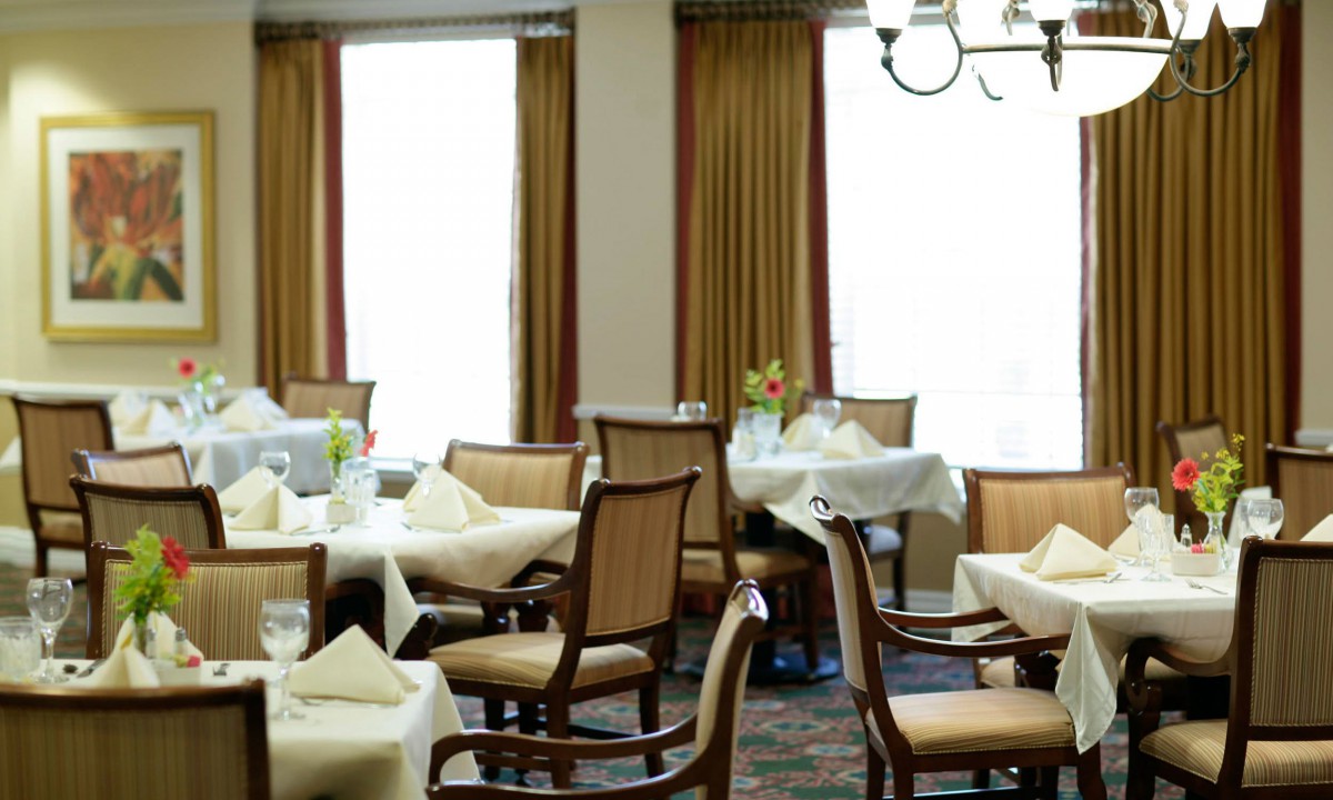 An elegant dining area with set tables and chairs, draped in soft lighting.