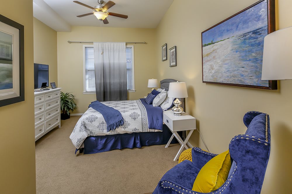 A cozy bedroom featuring a blue and white color scheme with a neatly made bed, nightstands, and wall art.
