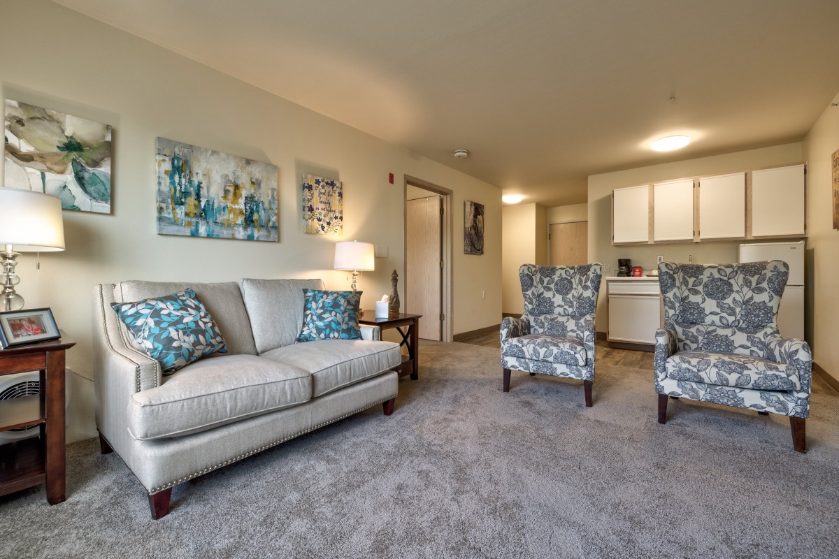 A cozy living room with a sofa, two armchairs, and decorative artwork on the walls.