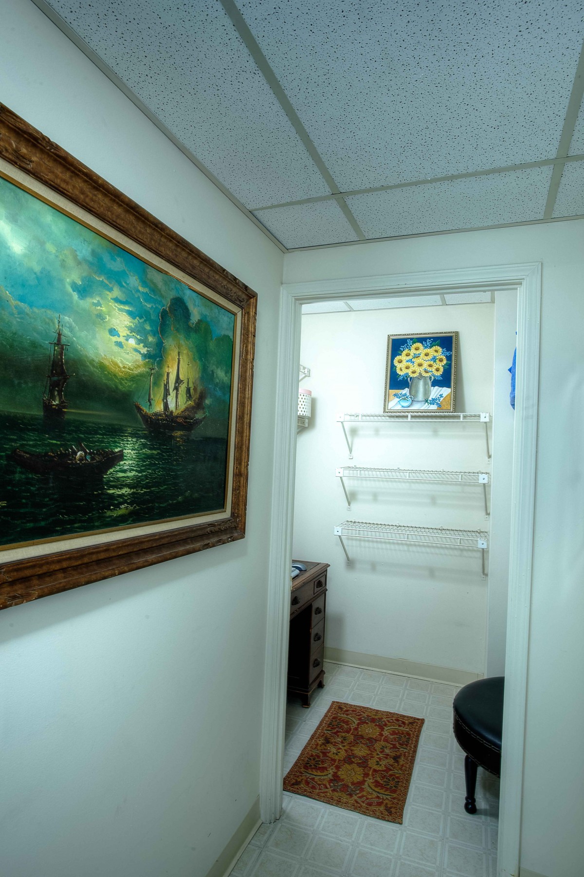A hallway with a nautical painting and empty shelves on the wall.