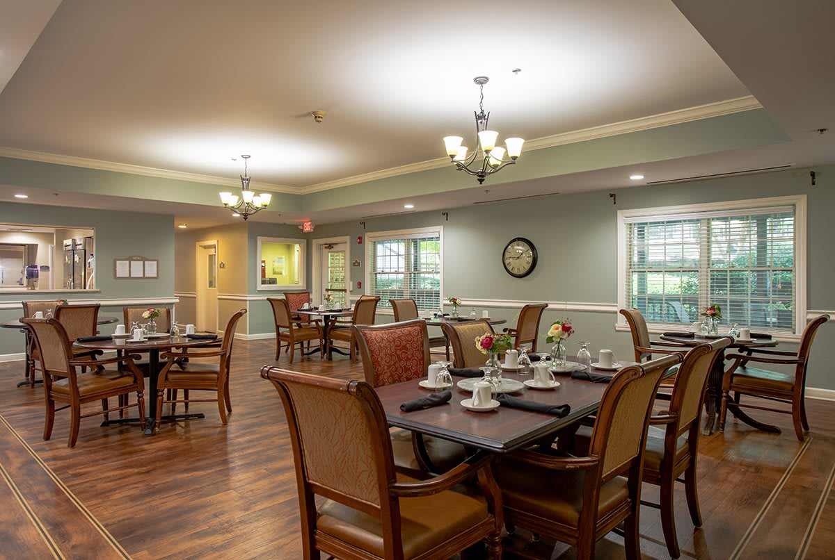 A well-decorated dining room with neatly arranged tables and chairs, featuring elegant chandeliers.