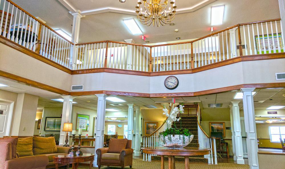 A spacious lobby with a grand chandelier, elegant furniture, and a staircase leading to a balcony.