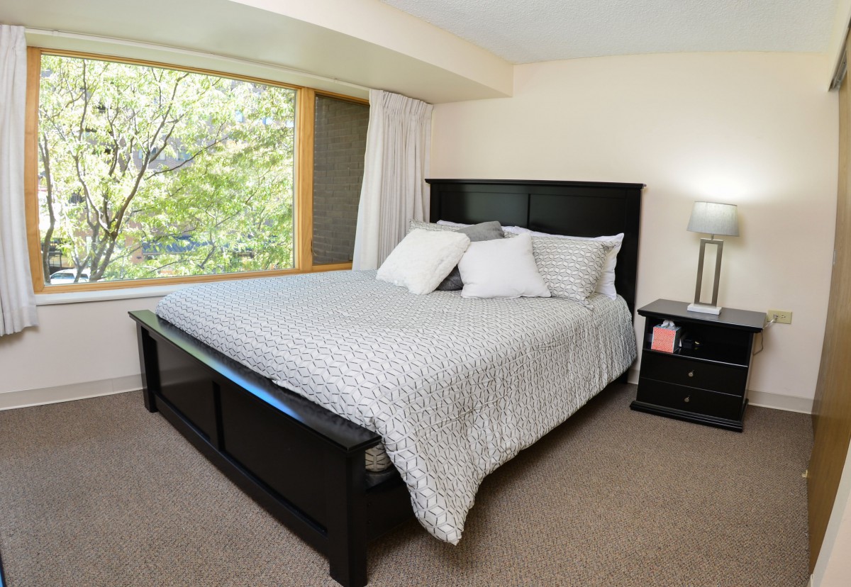A cozy bedroom with a large bed next to a window and nightstand.