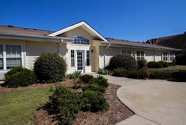 A residential house with landscaped shrubs and a clear blue sky.