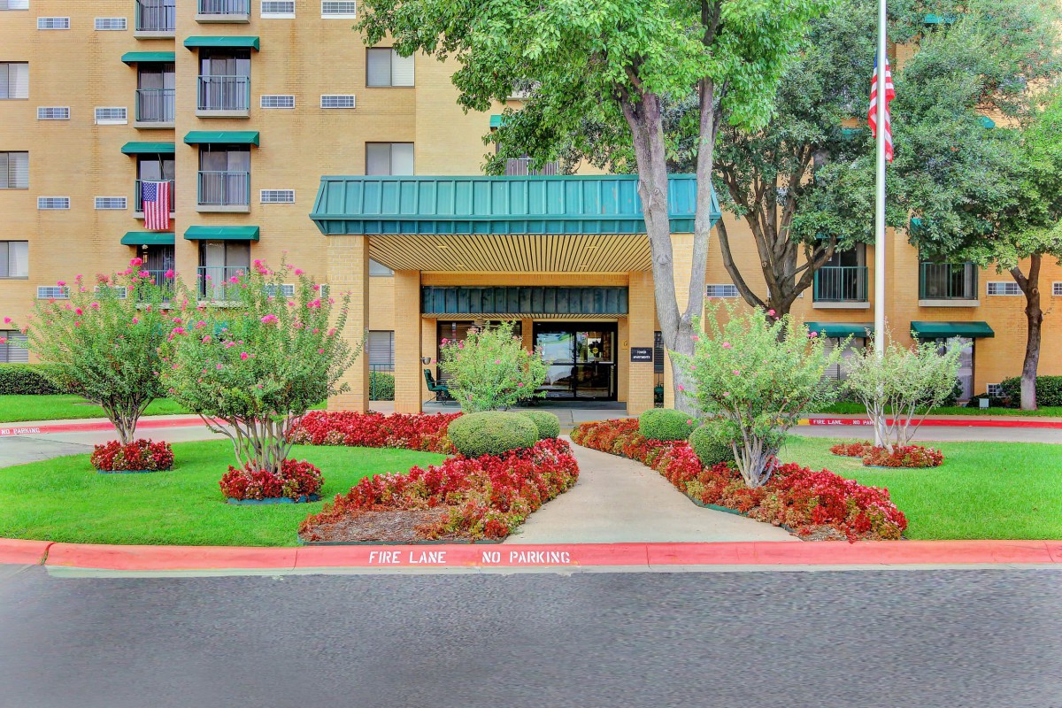 The entrance of a hotel with well-maintained landscaping and a clear pathway leading to the door.