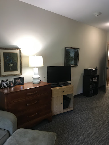 A cozy living room setup featuring a television, lamp, and wall art.