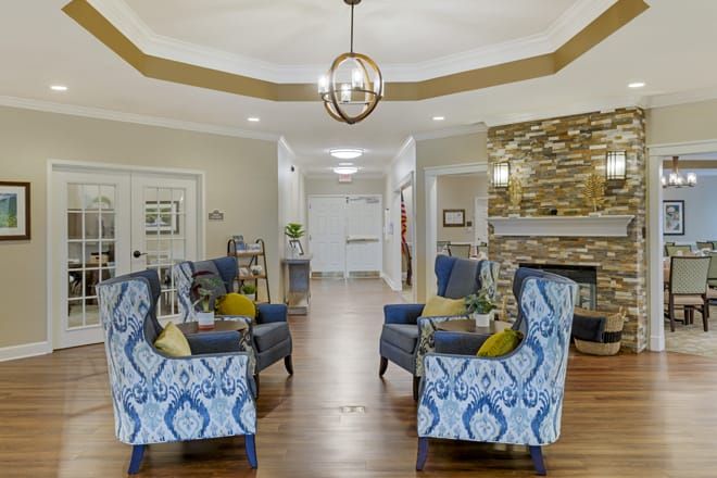 A modern and cozy living room with patterned armchairs arranged around a coffee table, featuring wood flooring and a stylish chandelier.
