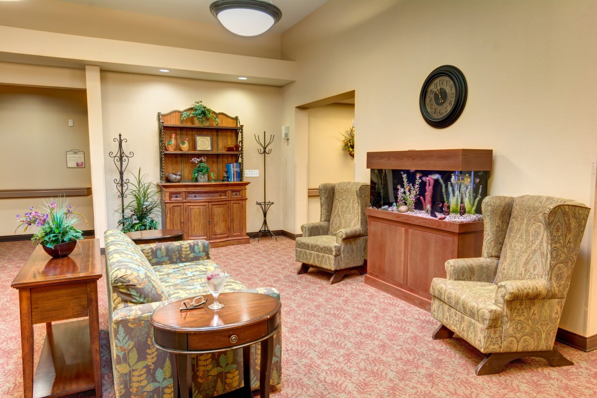 A cozy living room with comfortable seating, a bookshelf, and an aquarium.