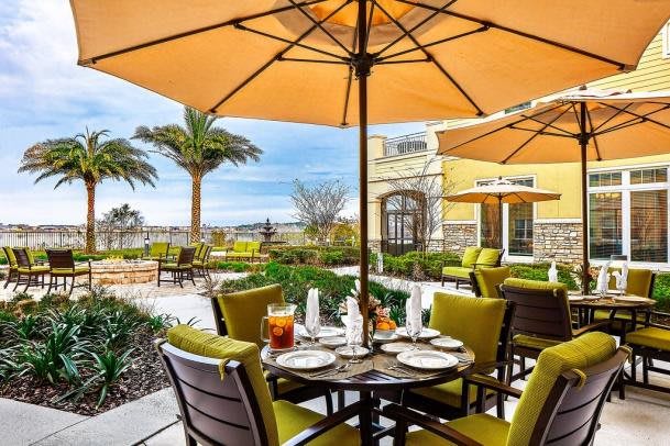 A charming outdoor dining area with tables and umbrellas, surrounded by palm trees and landscaped greenery.