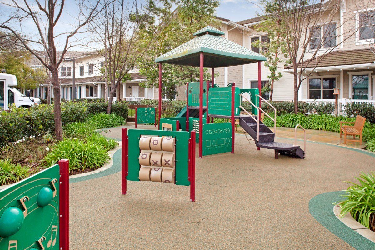 A colorful playground with various play structures in a residential neighborhood.