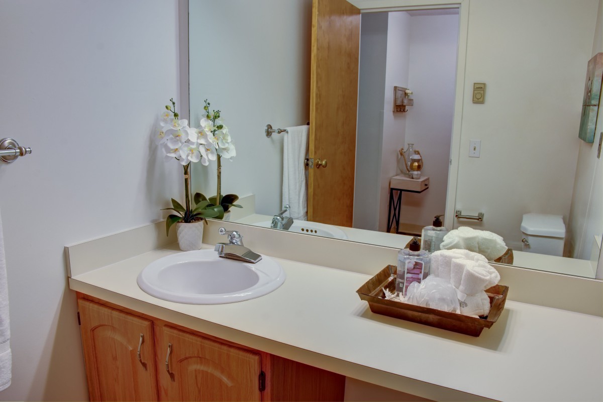 A tidy bathroom with a sink, mirror, and neatly arranged towels and decor.