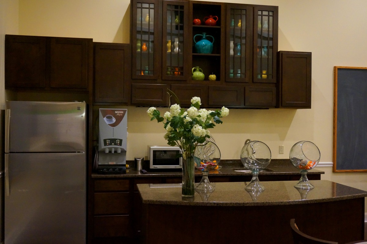 A modern kitchen with wooden cabinets, a countertop decorated with white flowers, and various appliances.