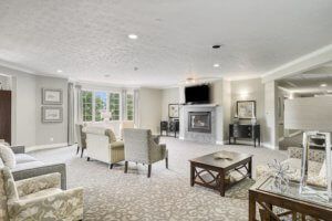 A spacious and elegantly decorated living room featuring a fireplace and television, with comfortable seating arrangements and a central coffee table.
