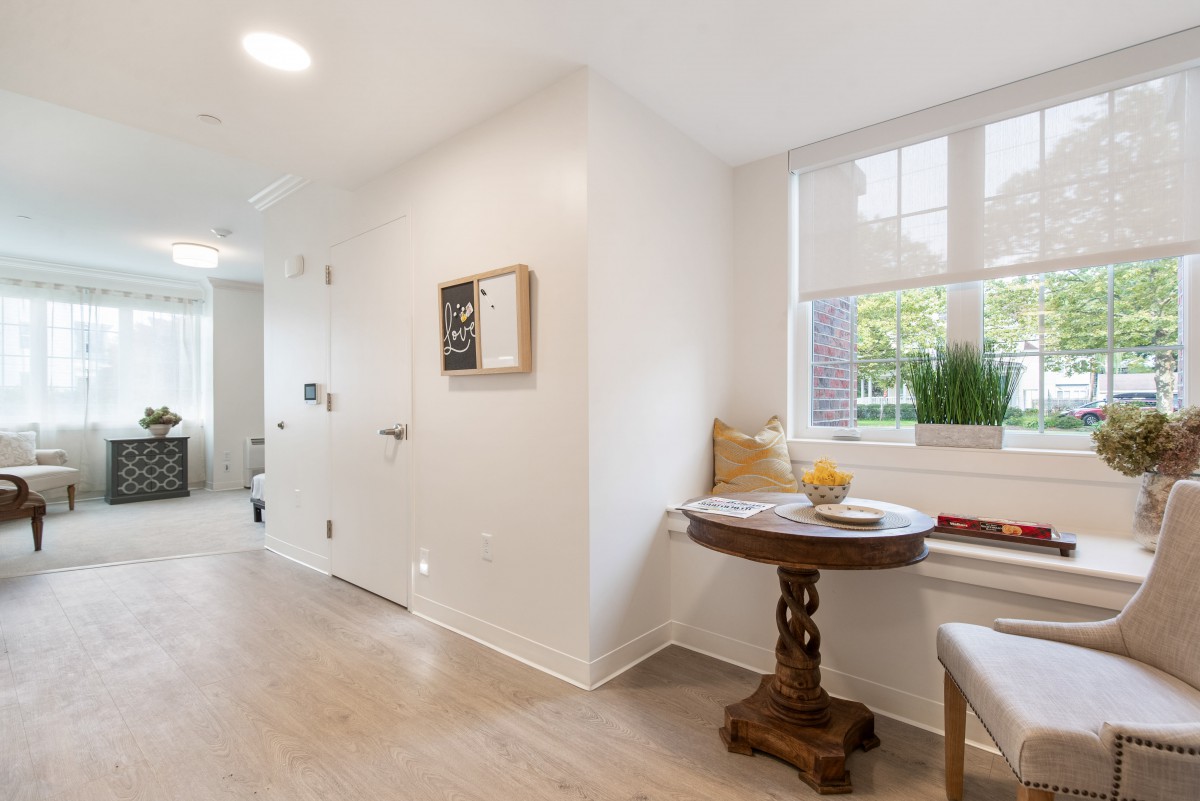 A bright and airy hallway with a cozy window seat and a small wooden table.