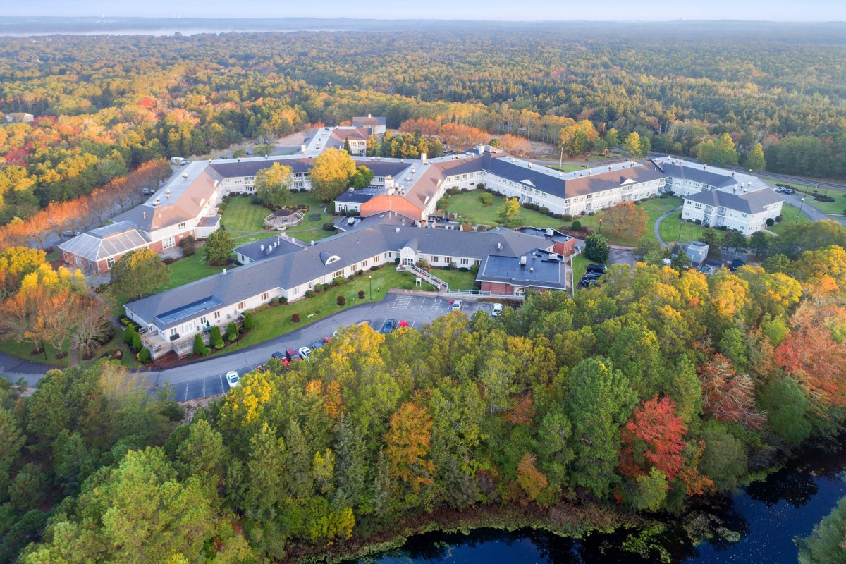 Aerial view of a building complex surrounded by colorful autumn foliage.