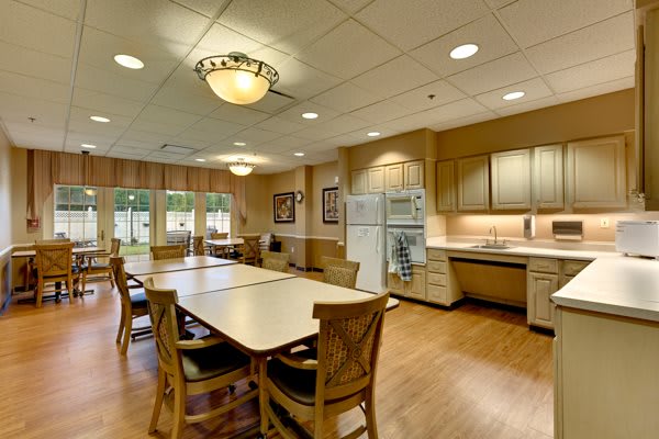 A spacious kitchen and dining area featuring a long table with chairs, cabinets, and appliances.