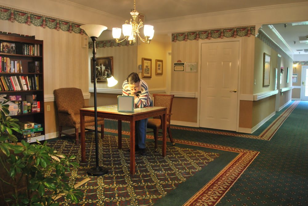 A person sits at a desk reading in a warmly lit room.