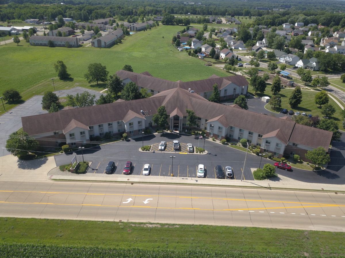 Aerial view of a large building with a parking lot, surrounded by a residential neighborhood and greenery.