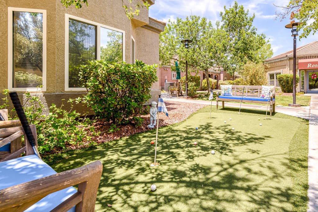 A backyard with a putting green and landscaped surroundings.