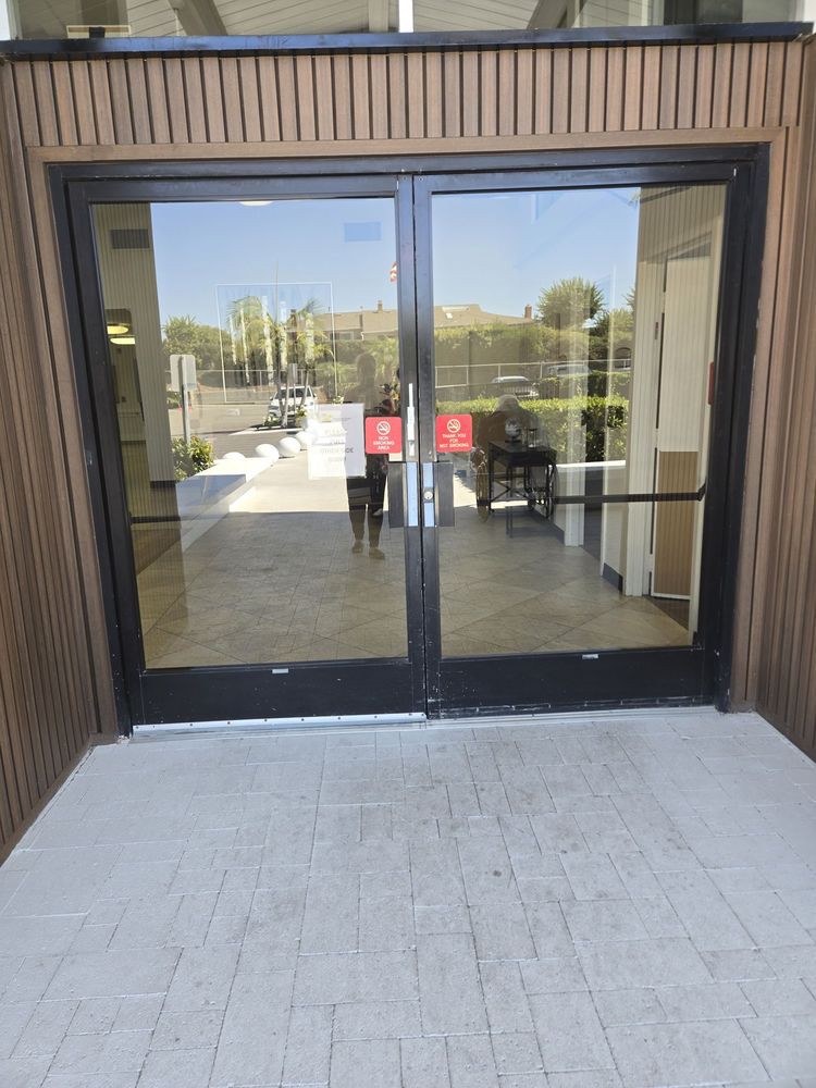 A glass entrance with automatic sliding doors reflecting the outdoor scenery.