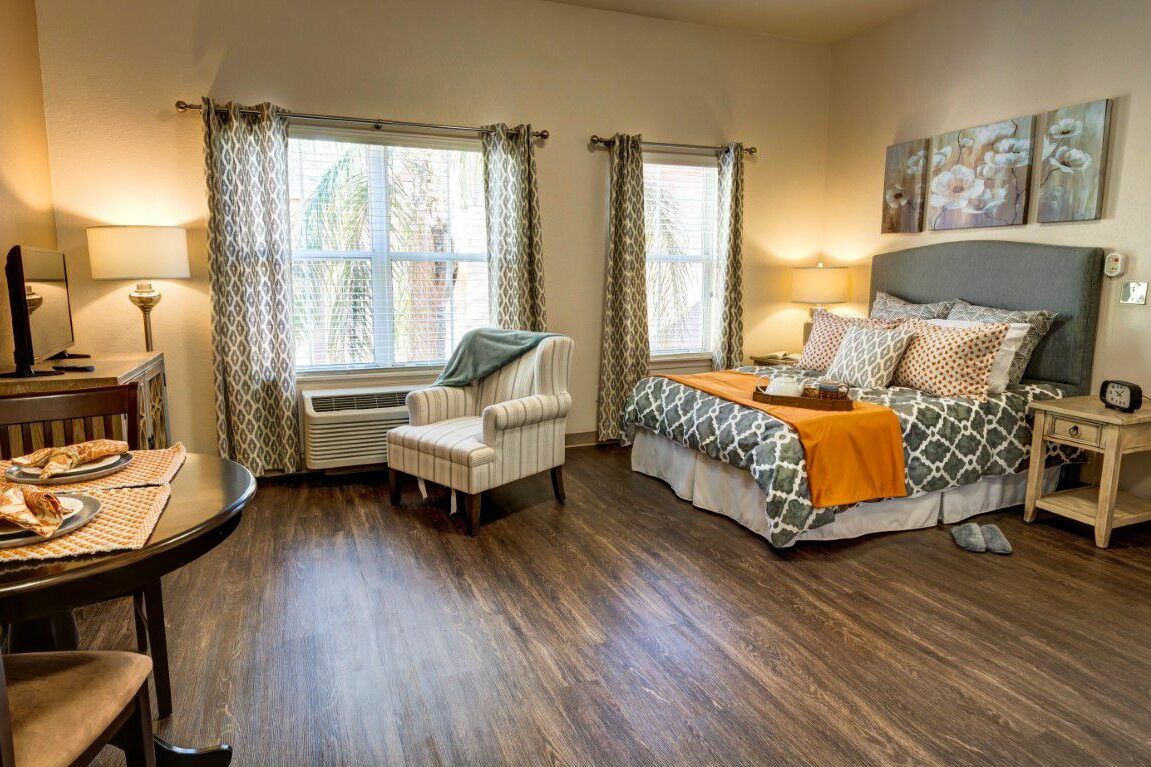 A cozy bedroom with natural light, featuring a stylish bed, patterned armchair, and elegant decor.