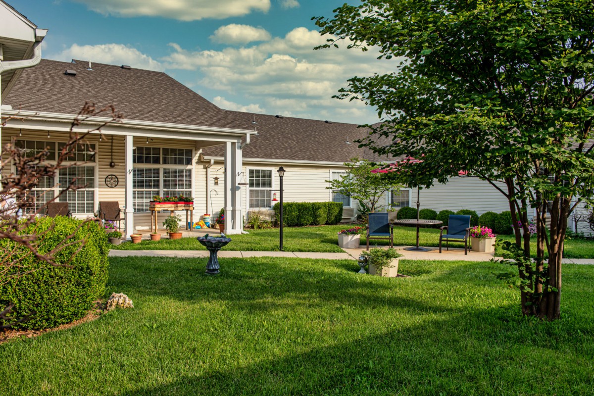 A serene backyard with a patio, lush green lawn, and outdoor seating area.