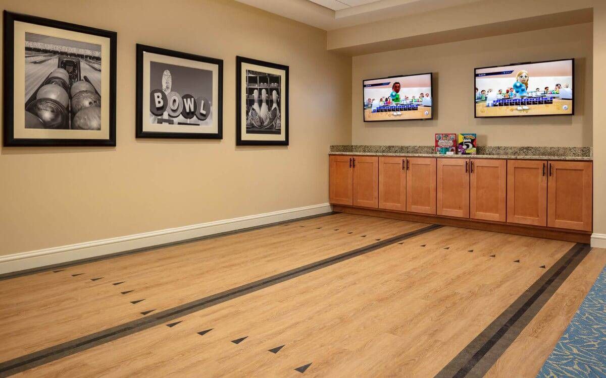 Art gallery room with framed pictures, wooden flooring, and wall-mounted televisions.