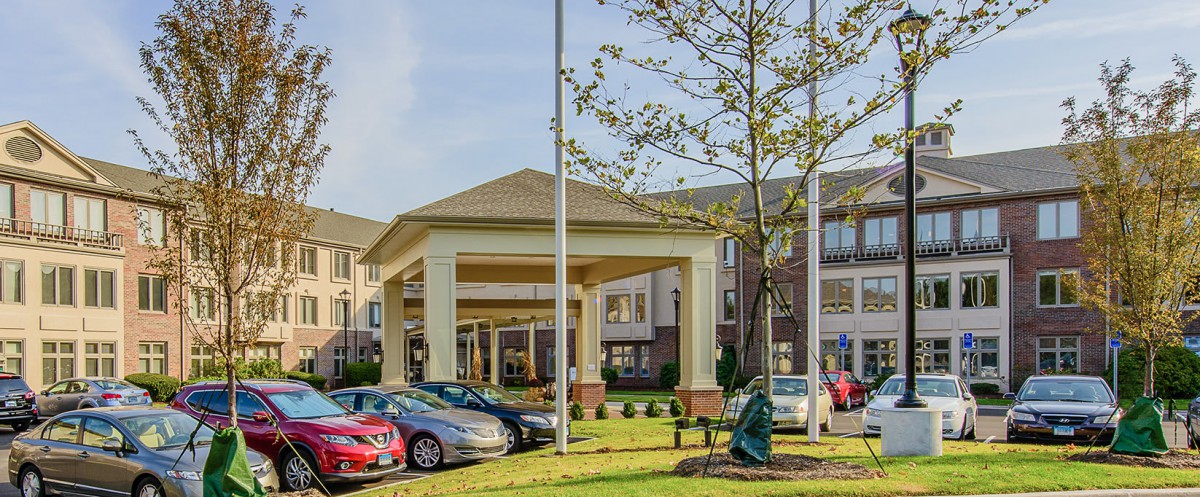 Exterior view of a hotel entrance with a parking lot and cars.