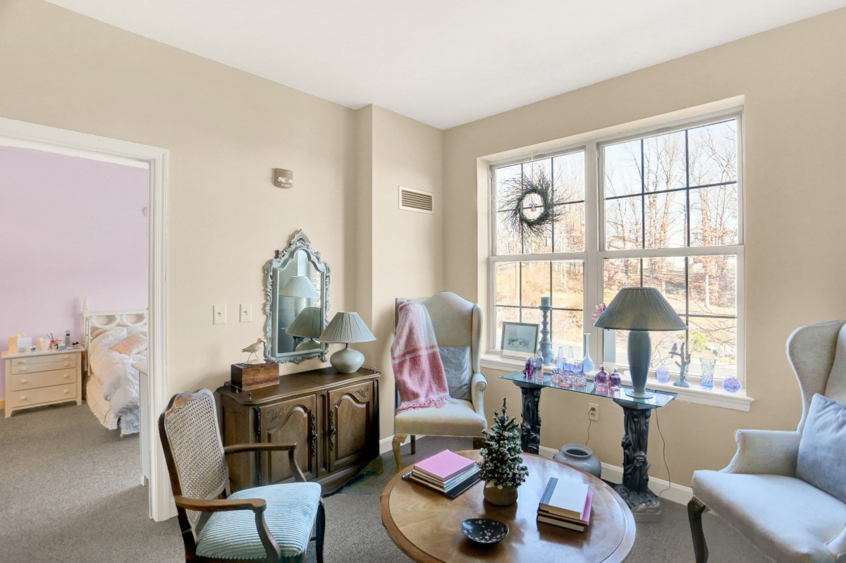 A cozy living room with elegant furniture and a large window allowing natural light to stream in.