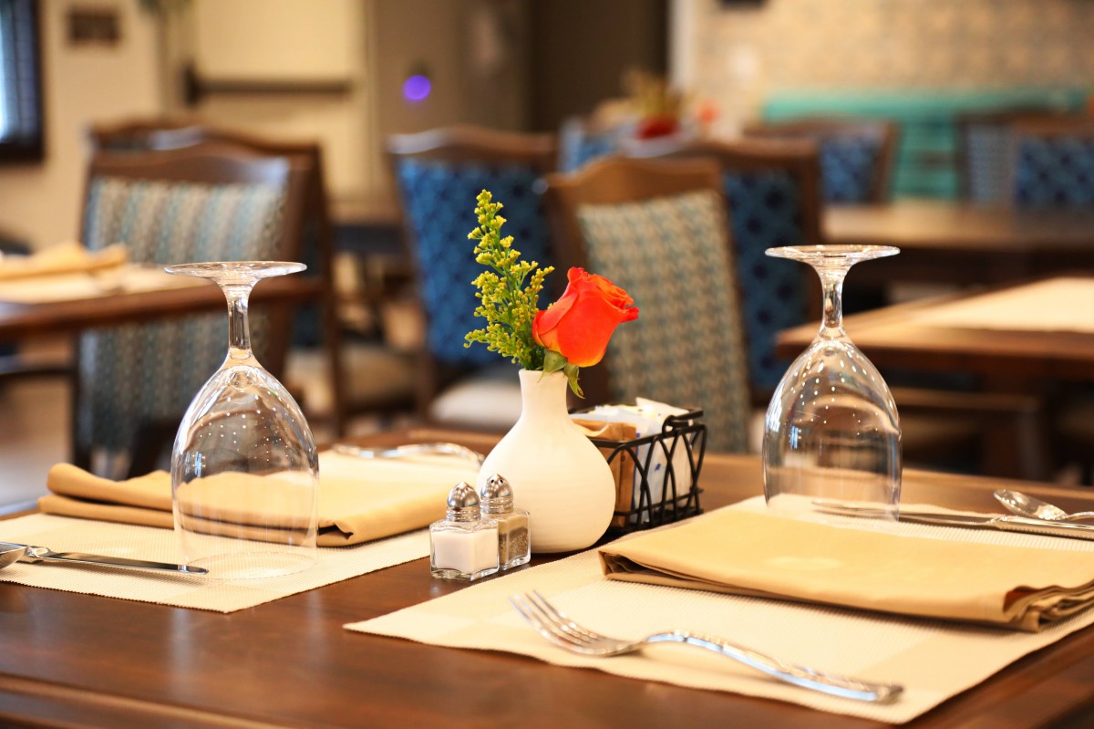 A neatly arranged restaurant table with wine glasses and a decorative flower vase.