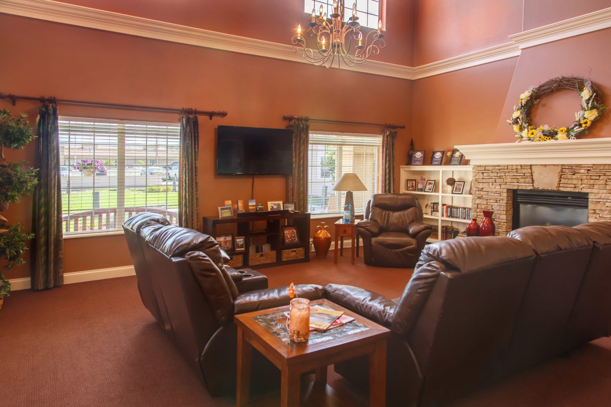 A cozy living room with leather seating, a chandelier, and a mounted TV.