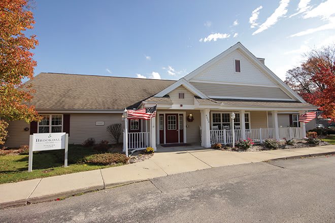 A suburban residential building with a welcoming entrance and porch under a partly cloudy sky.