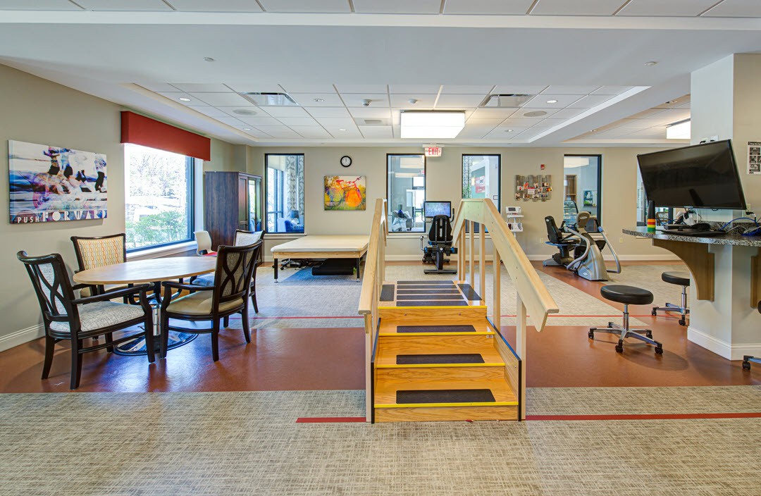 A spacious rehabilitation facility equipped with exercise equipment and a small set of stairs for physical therapy exercises.