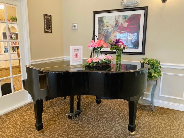 A grand piano decorated with flowers in an elegant room setting.