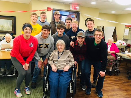 A heartwarming moment with an elderly woman surrounded by young men during a community gathering.