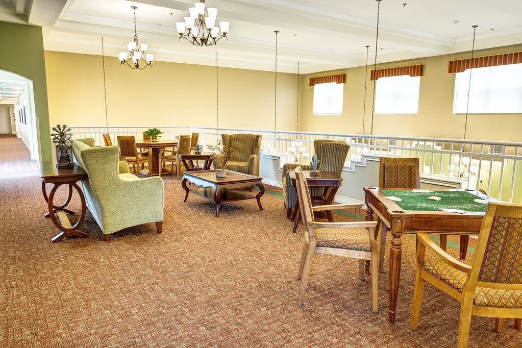 A well-furnished room with comfortable seating and tables, featuring elegant chandeliers.