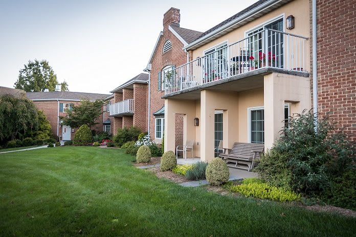 A view of residential apartments with balconies overlooking a well-maintained garden and lawn.