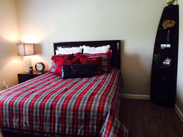 A cozy bedroom setup with a plaid-patterned bedspread and decorative pillows.