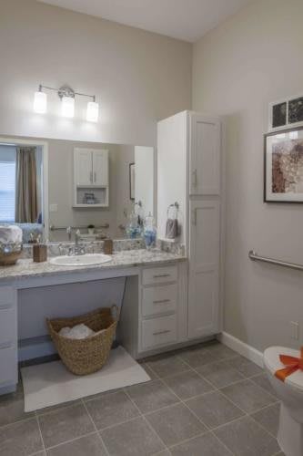A modern bathroom with a large mirror, double sink, and white cabinetry.