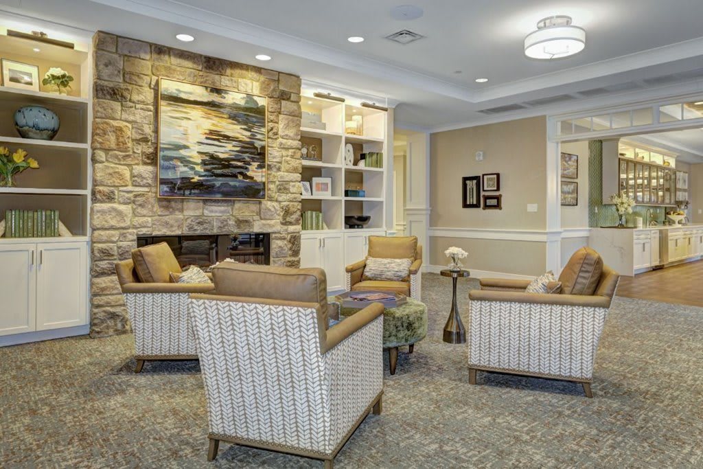 A cozy living room with a seating arrangement around a fireplace, featuring artwork and elegant decor.