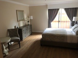 A cozy bedroom with a bed, dresser, chair, and window with curtains.