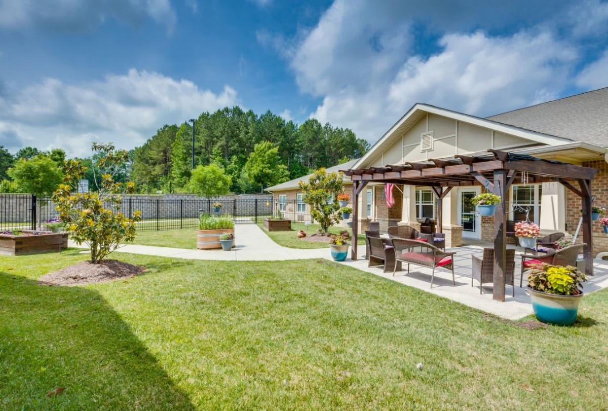 A well-maintained backyard with a pergola, outdoor seating, and a lush lawn.