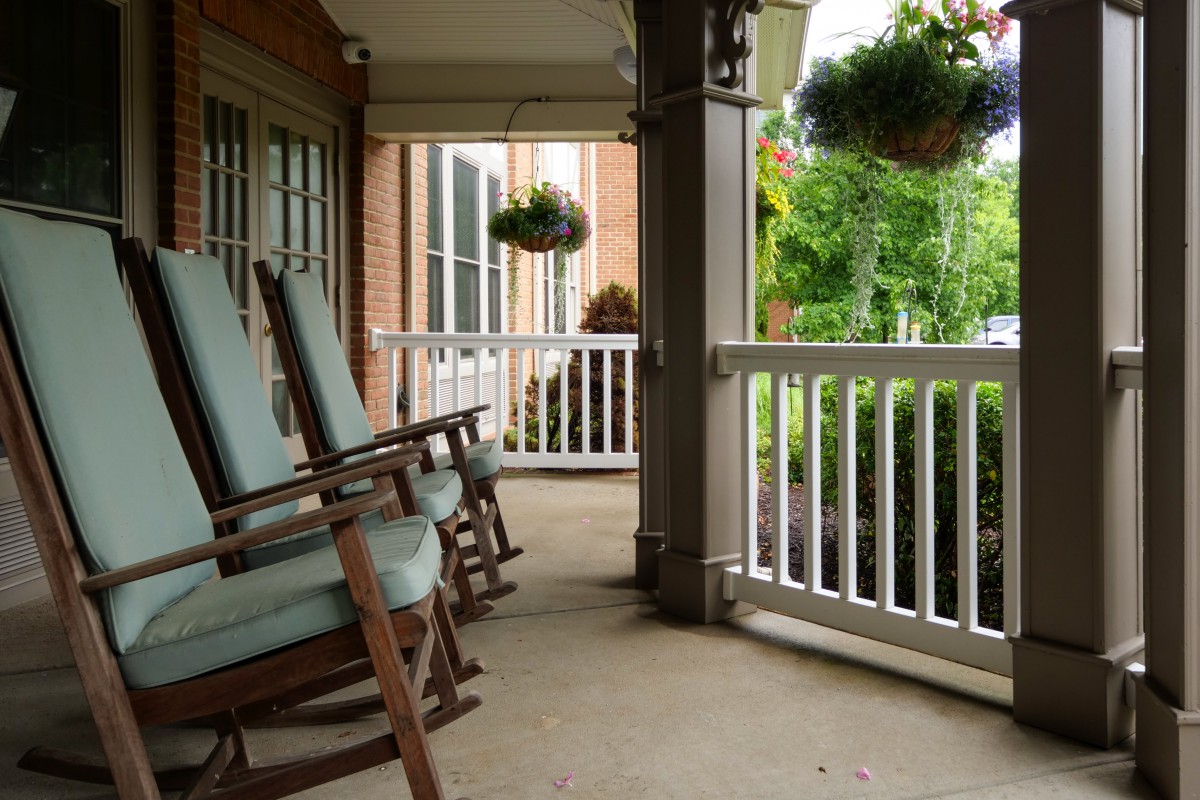 A cozy porch with rocking chairs and hanging plants, perfect for relaxation.