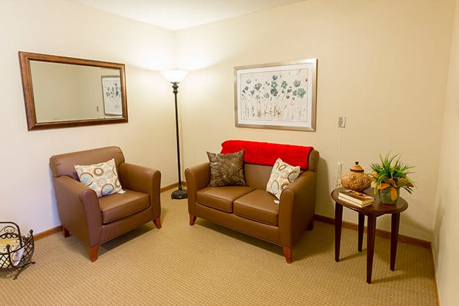 A cozy living room with two chairs, a floor lamp, and wall decor.