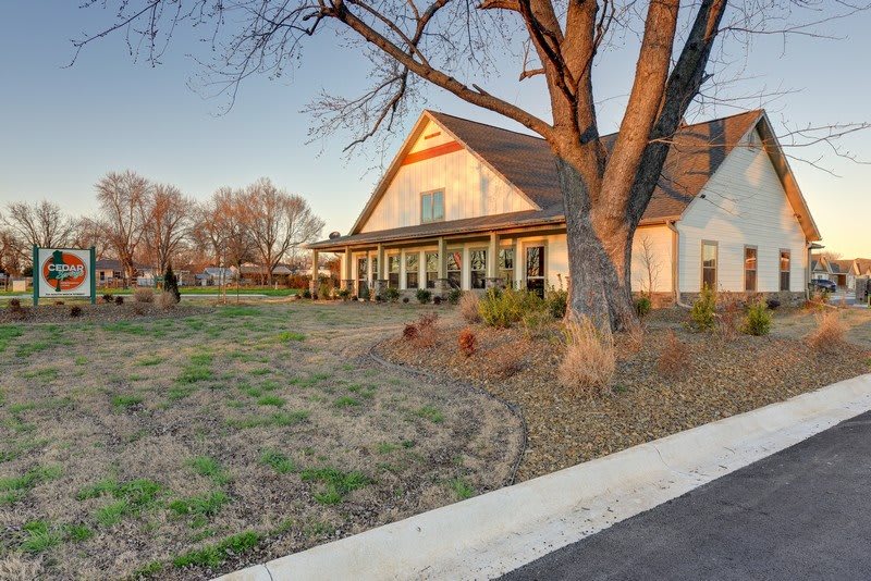 A charming house with a spacious porch surrounded by trees at sunset.