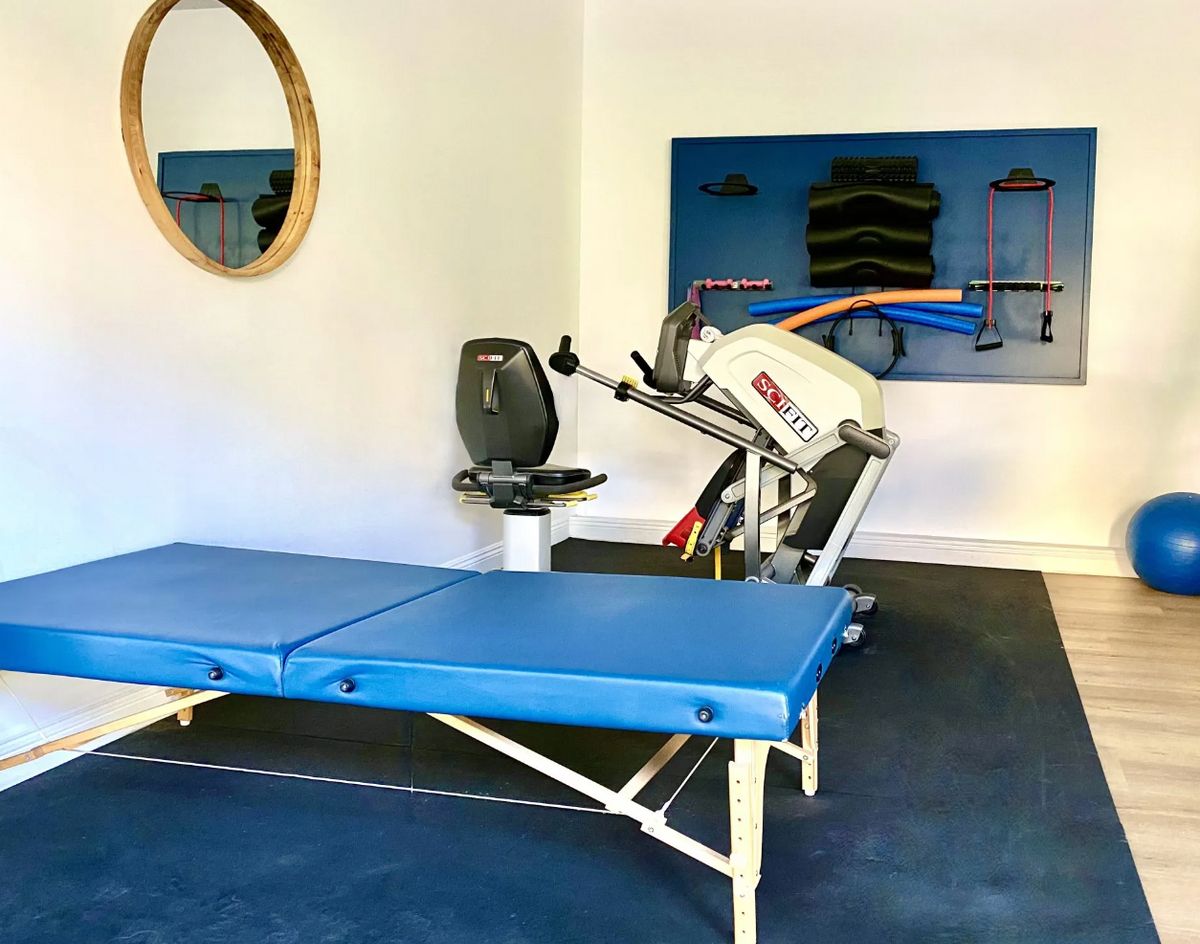 A physical therapy room equipped with a treatment table and exercise machine.