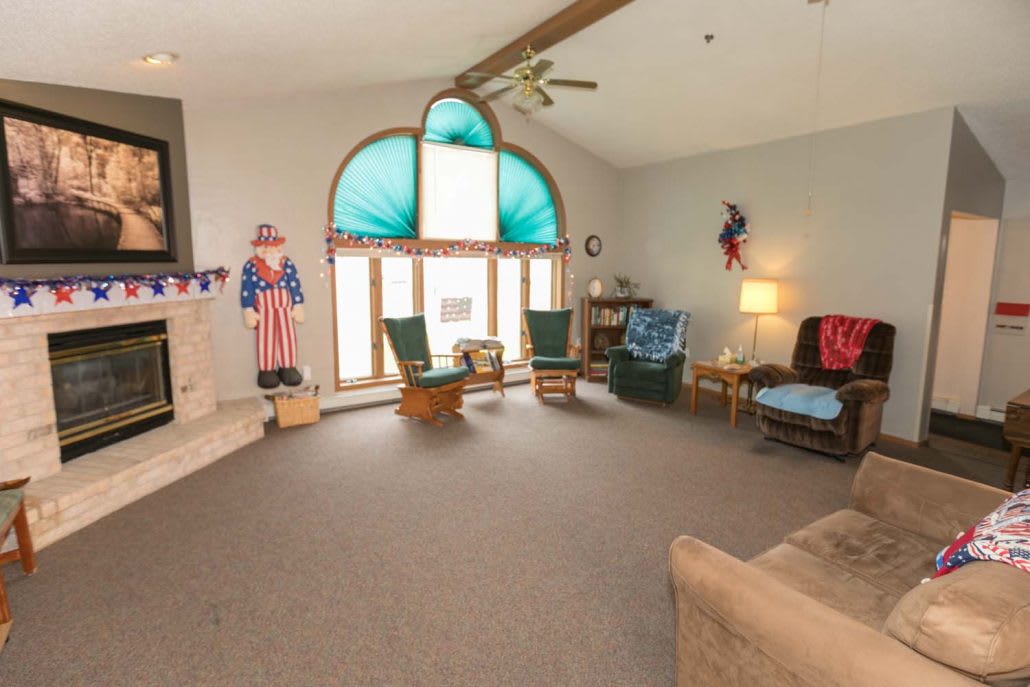 A spacious living room with high ceilings, featuring a large arched window and decorated in a patriotic theme.