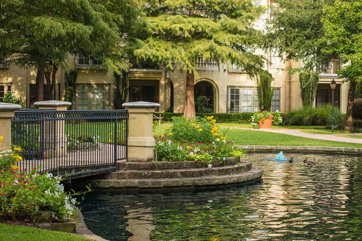 A landscaped garden with a pond and small bridge in an apartment complex.
