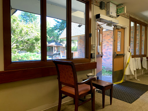A cozy waiting area with a chair and a view of the outdoors through large windows.