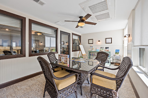 A modern office space featuring a glass table and comfortable seating, illuminated by natural light.